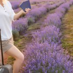 woman with suitcase and passport in lavender field.
