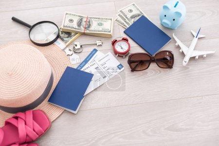 Téléchargez les photos : Tirelire rose, chapeau de paille, argent, passeport et lunettes de soleil sur table en bois. - en image libre de droit