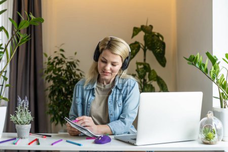 Photo for Meeting online. Young woman wearing headphones using laptop watching webinar or doing video chat by webcam. Business conference. E-learning education concept. - Royalty Free Image