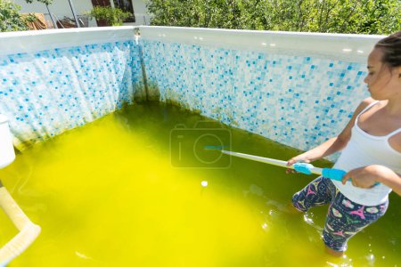 Téléchargez les photos : A little girl cleans a very dirty pool. - en image libre de droit