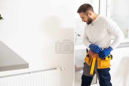 Foto de Reparación de calefacción radiador de primer plano. hombre reparando radiador con llave inglesa. Eliminación de aire del radiador - Imagen libre de derechos