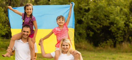 Foto de Día de la Bandera de la Independencia de Ucrania. Día de la Constitución. familia con la bandera de Ucrania en el campo. 24 de agosto. Vacaciones patrióticas - Imagen libre de derechos