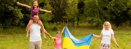 Foto de Día de la Bandera de la Independencia de Ucrania. Día de la Constitución. familia con la bandera de Ucrania en el campo. 24 de agosto. Vacaciones patrióticas - Imagen libre de derechos