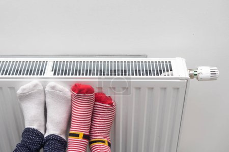 Téléchargez les photos : Réchauffement de la famille pieds près du chauffage à la maison, gros plan. - en image libre de droit