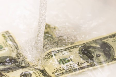 Foto de Dinero en efectivo que baja el drenaje del fregadero aislado sobre fondo blanco
. - Imagen libre de derechos