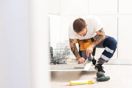 Téléchargez les photos : Craftsman repairs broken dishwasher. - en image libre de droit