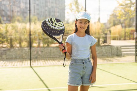 Foto de Little girl with racket playing padel tennis at court. - Imagen libre de derechos
