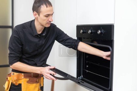 Reparatur von Geräten. Mann installiert Elektroherd in der Küche.
