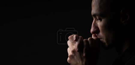 Téléchargez les photos : Portrait d'un bel homme priant sur fond gris
. - en image libre de droit