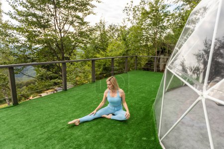 Téléchargez les photos : A woman is doing exercises on the terrace of a transparent bubble dome. - en image libre de droit