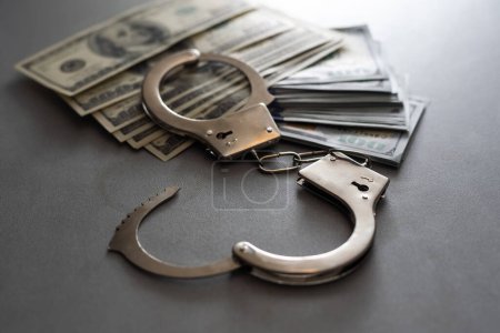 Photo for Handcuffs and one hundred dollars on the wooden table. - Royalty Free Image