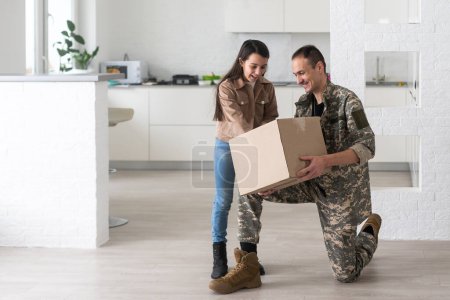 Foto de Military parents with daughter hugging, near cardboard boxes. - Imagen libre de derechos