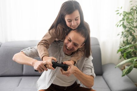 Photo for Excited father and daughter playing video game at home - Royalty Free Image