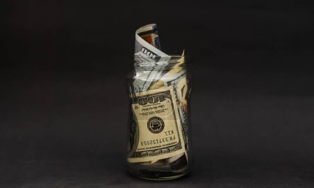 Foto de Many 100 US dollars bank notes in a glass jar isolated. - Imagen libre de derechos