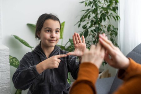 Kleine kaukasische Teenie-Mädchen machen Artikulationsübungen mit fürsorglicher Mutter oder Lehrerin zu Hause. Kleines Kind spricht Laute aus, spricht mit Tutor oder Trainer, übt sich gemeinsam in Stimmaussprache.