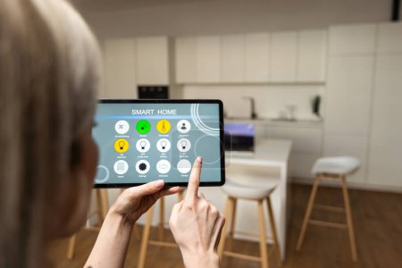 Téléchargez les photos : Iot Smart Home Concept - rear view of woman ask digital tablet to set temperature of air conditioner more higher by voice at home and all the electric meter in house getting energy-efficient. - en image libre de droit