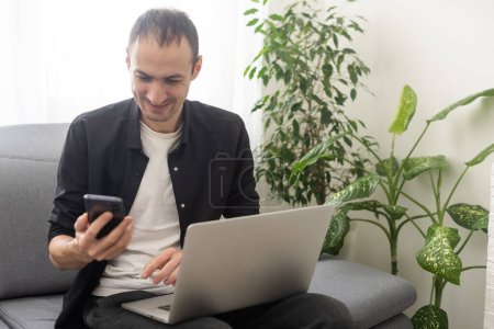 Foto de Young happy businessman smiling while reading his smartphone. Portrait of smiling business man reading message with smartphone. - Imagen libre de derechos