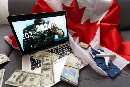Foto de Portátil con avión, dinero y bandera de Canadá. - Imagen libre de derechos