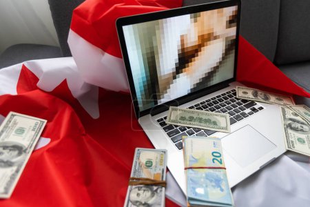 Photo for Laptop with blurred screen, money and Canadian flag. - Royalty Free Image
