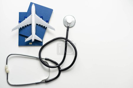 Foto de Turismo Médico, concepto de viaje médico. Estetoscopio, avión de juguete y pasaporte sobre fondo gris - Imagen libre de derechos