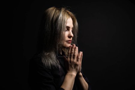 Photo for Woman praying with hands together on black background. - Royalty Free Image