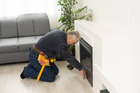 an elderly man repairs a fireplace.