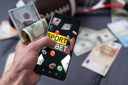 Smartphone mit mobiler Glücksspiel-Anwendung, Ball und Geldscheinen. Sport- und Wettkonzept.