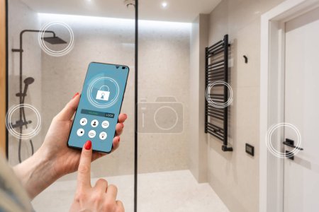 Close up smartphone in female hand with smart home system app interface on cellphone screen, young woman controlling all house system by phone in modern apartment, internet of things concept
