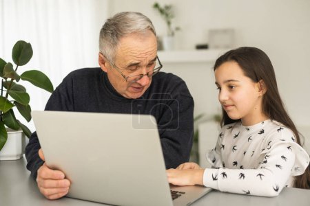 Photo for Grandfather and granddaughter spend time together use laptop, browse website, younger generation teach explain to older how to use modern tech concept. - Royalty Free Image