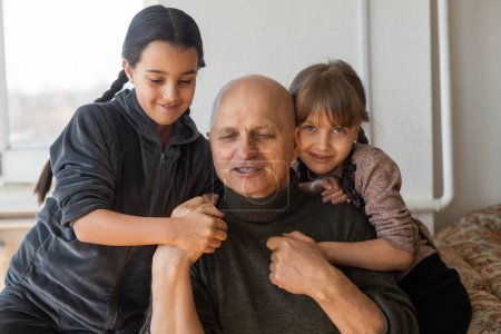 Photo for Ukrainian grandfather and two granddaughters hugging. - Royalty Free Image
