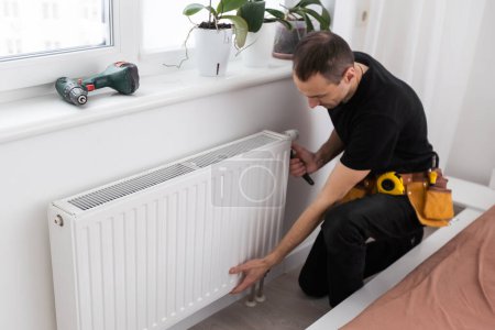 Photo for Repair heating radiator close-up. man repairing radiator with wrench. Removing air from the radiator. High quality photo - Royalty Free Image