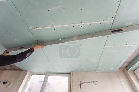 Foto de Hombre ensambla marco de metal de perfil para techos de placas de yeso. Foto de alta calidad - Imagen libre de derechos