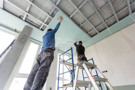 Téléchargez les photos : Deux hommes aident pour la construction du plafond. Photo de haute qualité - en image libre de droit