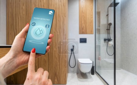 Téléchargez les photos : Téléphone intelligent avec application de contrôle à domicile avec de l'eau détectée. - en image libre de droit