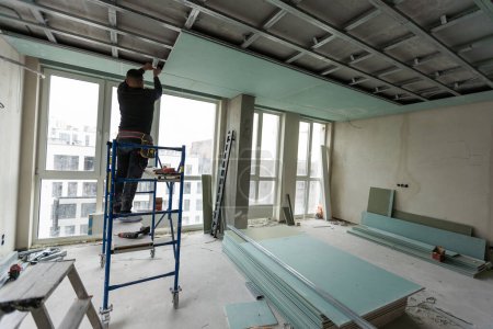 Téléchargez les photos : Les travailleurs assemblent un plafond suspendu avec cloison sèche. Photo de haute qualité - en image libre de droit