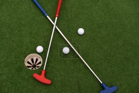 Téléchargez les photos : Putters de golf colorés avec des balles de golf sur gazon synthétique. - en image libre de droit