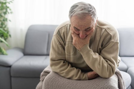 Frustrado infeliz hombre maduro de mediana edad sentado en el sofá, sintiéndose deprimido solo en casa. Confundido abuelo jubilado mayor preocupándose por la difícil decisión de la vida, espacio de copia, la soledad de las personas mayores.