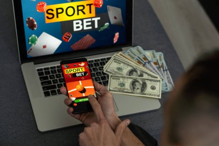 Homme regardant le football jouer en ligne diffusé sur son ordinateur portable, acclamant pour son équipe préférée, faire des paris sur le site bookmakers.