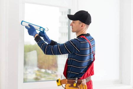 Téléchargez les photos : Ouvrier de la construction étanchéité fenêtre avec calfeutrage intérieur
. - en image libre de droit