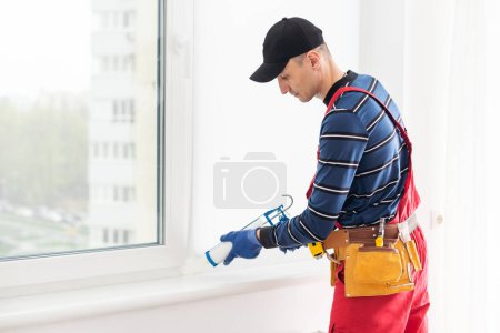Téléchargez les photos : Ouvrier de la construction étanchéité fenêtre avec calfeutrage, gros plan. - en image libre de droit