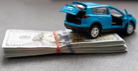 Téléchargez les photos : Une voiture jouet et des billets de banque mensonge, le coût de fonctionnement d'une voiture - en image libre de droit