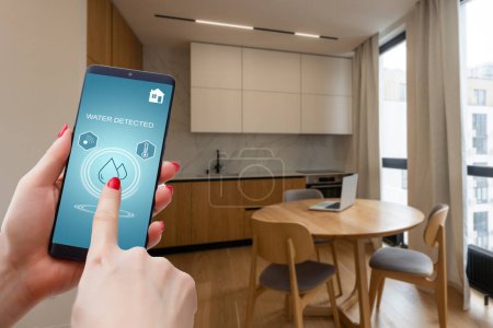 Handhaltendes Smartphone mit Home Control Applikation mit Wassererkennung, Smart Home Konzept