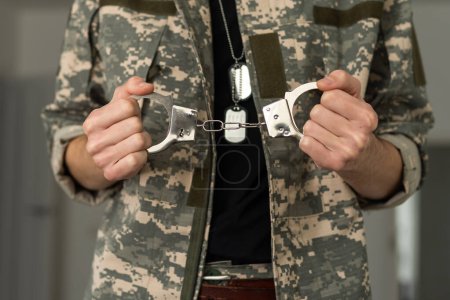 Un soldado esposado detrás de las rejas contra un fondo negro. Concepto: corte marcial, negativa a movilizarse, crimen en el ejército