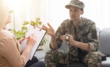 Photo for Sad soldier with ptsd talking at psychiatrist and gesturing while sitting on couch during therapy session. - Royalty Free Image