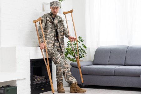 Téléchargez les photos : Soldat en uniforme militaire kaki sur béquilles. - en image libre de droit