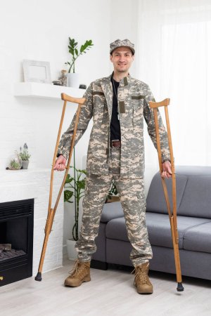 Photo for Soldier in khaki military uniform on crutches. - Royalty Free Image