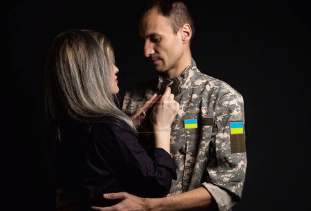 Photo for Soldier in military uniform reunited with his family and Ukrainian flag. - Royalty Free Image