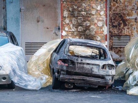 Téléchargez les photos : Une vue de face recadrée d'une voiture rouillée brûlée et abandonnée. - en image libre de droit