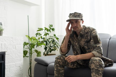 Foto de Un hombre con uniforme militar está sentado en una silla junto a la ventana. Concepto: un soldado en una cita de psicólogos, síndrome de estrés postraumático, trastorno mental, las consecuencias de la guerra. - Imagen libre de derechos