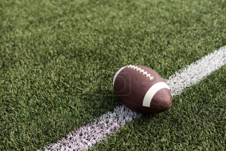 American football ball on green grass field background